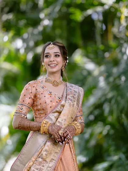 A joyful, candid shot of the bride in a beautiful garden setting. The natural light makes her skin glow, and her smile is infectious.