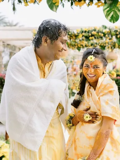 A sweet, candid moment of the couple covered in turmeric and flower petals after their Haldi ceremony.