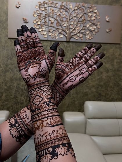 A crossed-arm pose to showcase the full narrative of the baby shower mehendi, from the baby in the cradle to the procession of elephants.
