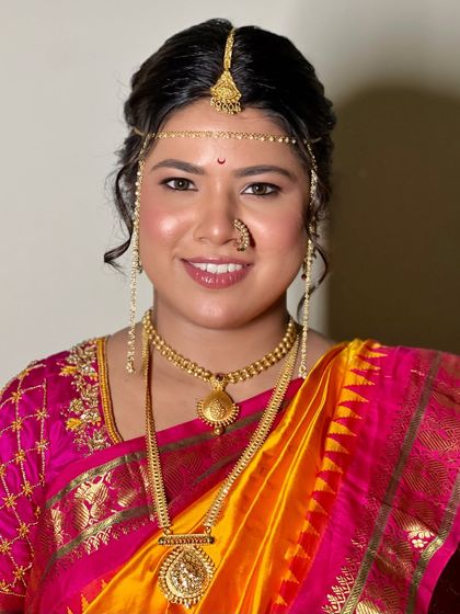A full view of the classic Maharashtrian bridal look. The makeup is designed to harmonize with the intricate gold jewelry and traditional headpiece.