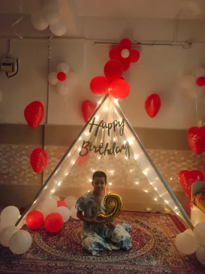 We also create cozy and intimate setups for home celebrations. This fairy light tent provides a magical space for a 9th birthday, complete with red and white balloon decorations.