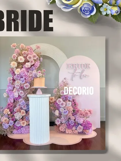 This pastel floral 'Bride to be' setup offers a softer, more romantic aesthetic. The design uses two arched backdrops and an explosion of pink and lavender flowers, with a dedicated pedestal for the cake.