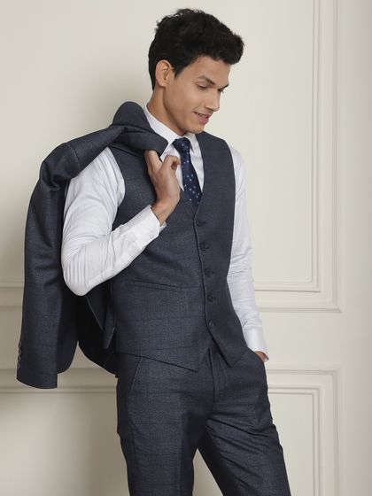 The navy blue suit styled with the jacket off, showing the versatility of a three-piece suit. The waistcoat look is timeless.