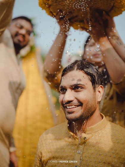 The groom, Adi, enjoying the Haldi rituals. The shower of water and flowers makes for a dynamic and celebratory shot.