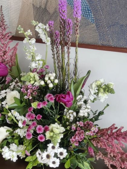 A close-up of a modern floral bouquet. The mix of textures, from the feathery pink astilbe to the spiky purple liatris and delicate daisies, creates a visually interesting and artistic composition.
