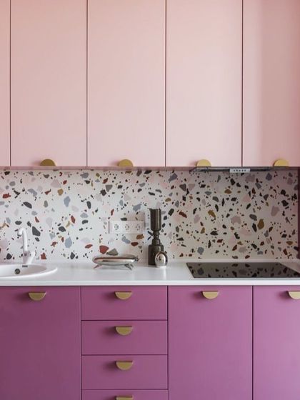 A playful two-tone pink kitchen featuring a terrazzo-style backsplash. The combination of light and dark pink cabinets with minimalist gold handles adds a touch of retro charm.