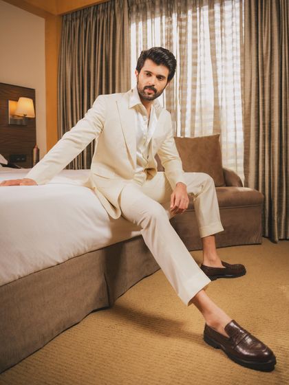 A crisp, all-white three-piece suit by OSBYOS for Vijay Deverakonda. Styled for a Prime Video event, this look is clean, confident, and effortlessly cool, especially when paired with classic brown loafers.