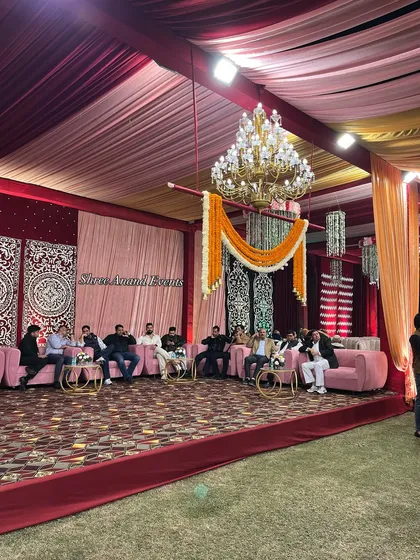 Guests enjoying the celebration in a comfortable lounge area, featuring pink sofas and ornate backdrops under a grand chandelier.