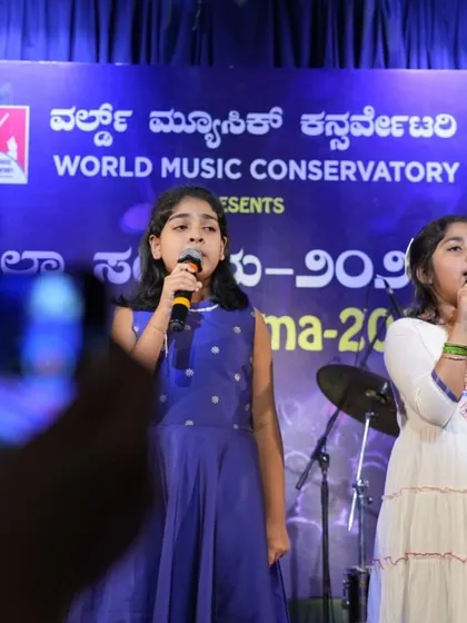 A wider shot of the patriotic duet, showing the students performing confidently in front of the audience and our large event banner.