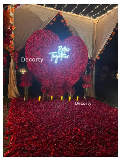 The giant red rose heart backdrop illuminated at night, creating a dramatic and romantic focal point.