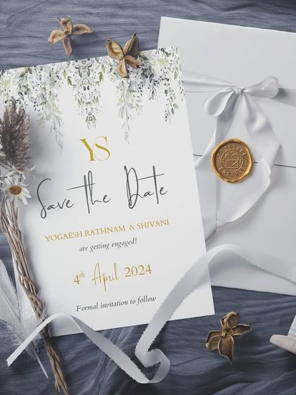An enchanting Save the Date card featuring a delicate watercolor leaf design and a custom monogram. The accompanying envelope is sealed with a white ribbon and a custom gold wax seal, adding a touch of old-world romance.