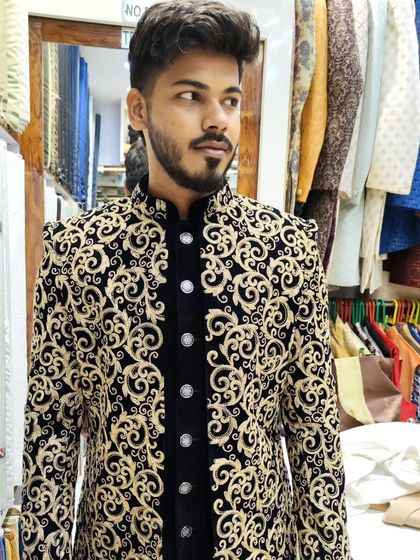 This open sherwani features all-over gold embroidery on black fabric, layered over a velvet jacket. It's a luxurious and regal option designed for a groom's special day.