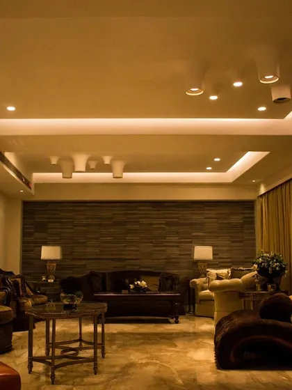 The living room of the Punjab Kesari Residence, showcasing a layered lighting approach. I combined indirect cove lighting for general ambiance with adjustable surface-mounted spotlights that can be directed to highlight the textured wall or specific seating areas.