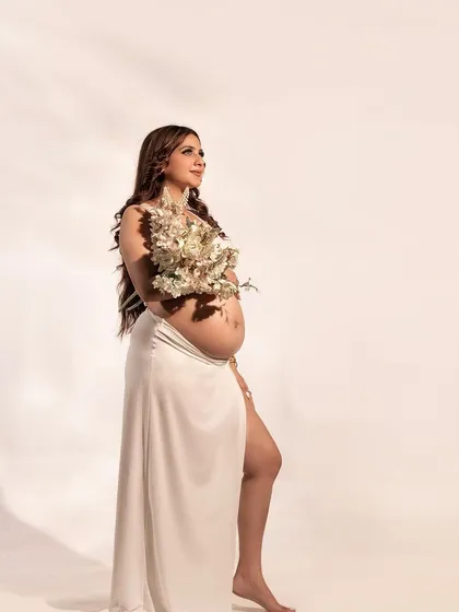A portrait of hopeful anticipation. The mother-to-be, adorned with a bouquet of white flowers, looks towards the light, creating a beautiful and symbolic image.