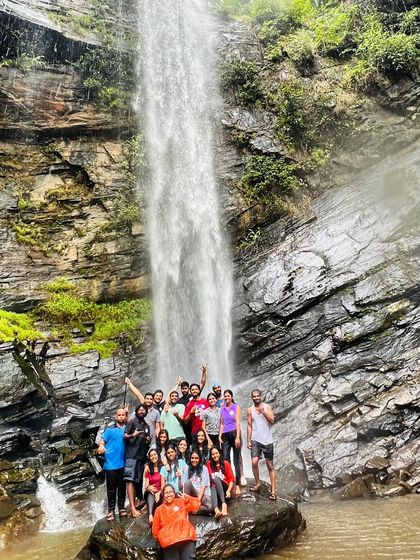 The group posing on a rock in front of a tall waterfall.