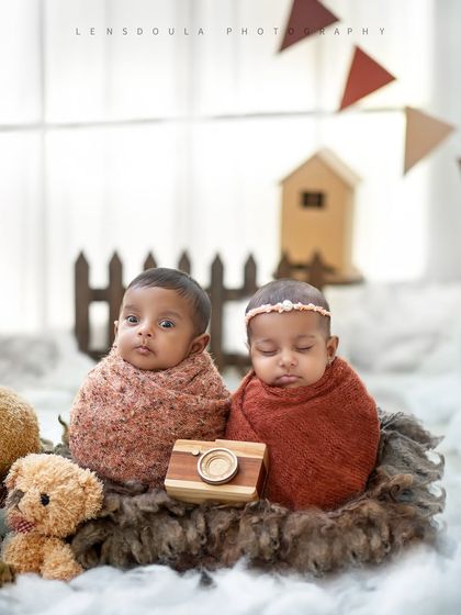 Perfectly posed side-by-side, this portrait captures a quiet moment between two newborn twins amidst a charming teddy bear picnic theme.