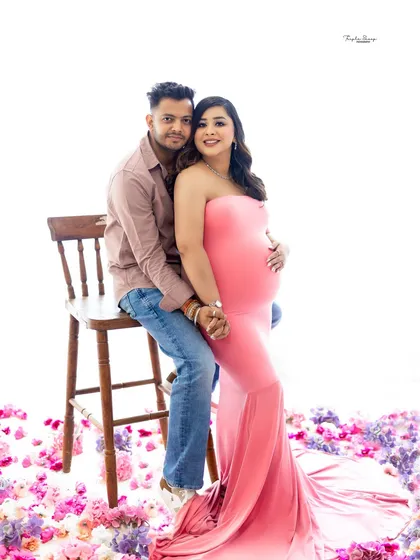 A comfortable and intimate seated pose for an expecting couple. The floor scattered with flowers complements the color of the maternity gown perfectly.