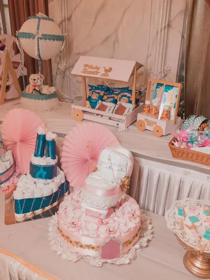 A modern and cute candy and diaper cake table for a baby shower, featuring a pink and blue theme.