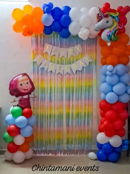 Here's a fun Masha and the Bear themed birthday decoration. It features a rainbow tinsel curtain, a colorful balloon arch with a unicorn foil balloon, and a Masha character standee, creating a bright and cheerful party backdrop.