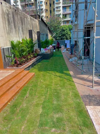 A long view of the new lawn installed at the Lodha villa, running alongside the building and a new wooden deck area.