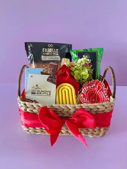 This Kauna basket with a handle is filled with premium chocolates and snacks. The red ribbon and decorative elements make it perfect for any celebration.