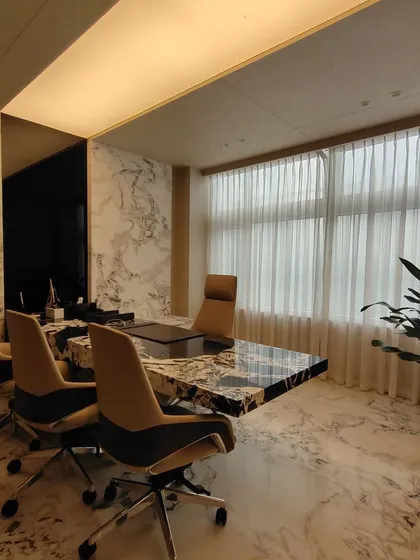 The executive meeting room at the RS head office in Chennai. The space is defined by a statement meeting table made from a single piece of heavily veined marble, complemented by floor-to-ceiling marble walls and soft, natural light to create an atmosphere of quiet authority.