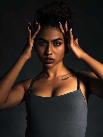 A powerful and intense studio portrait. I used a dark background and focused lighting to sculpt the model's features and create a commanding presence. The pose, with hands framing the face, draws the viewer's eyes directly to her intense gaze.