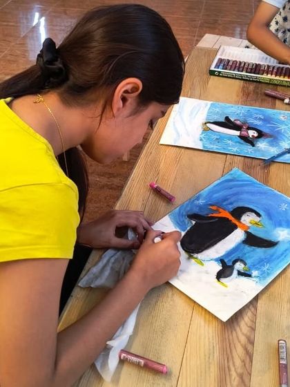 Another student in our penguin art class, adding details to her piece with soft pastels. This project is a favorite during our winter-themed sessions.