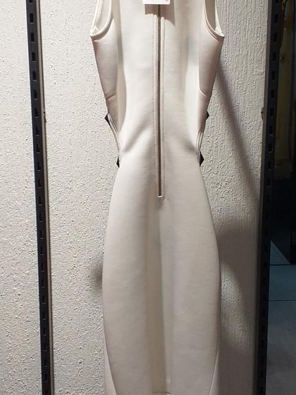The back view of a modern white sheath dress, showing a full-length zipper and clean lines. This highlights the quality construction of our designer pieces.