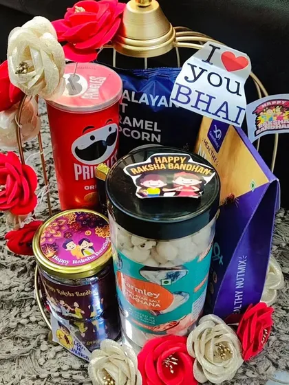 Another view of the golden birdcage Rakhi hamper, adorned with paper flowers and "I Love You Bhai" tags.