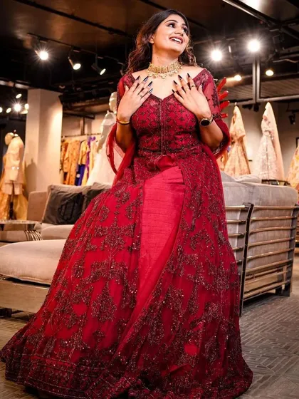 This image captures the elegance of a red embroidered gown from the Study by Janak collection. The model's joyful pose and the luxurious store background create an aspirational image for prospective clients.