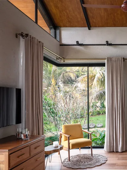 A quiet corner in the Grove House bedroom, where a comfortable armchair is perfectly positioned to enjoy the view of the lush garden. The design prioritizes connection to nature, making it an ideal space for relaxation.