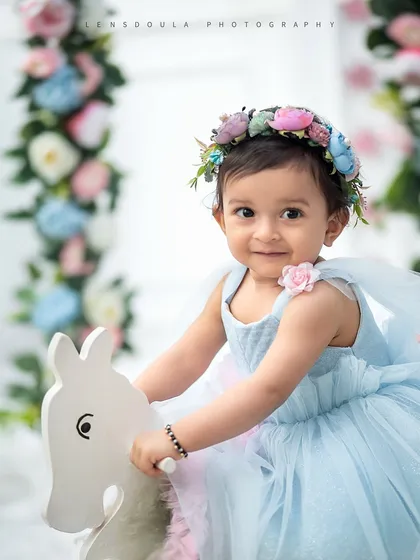 A close-up of our little flower fairy on her rocking horse, framed by a beautiful floral swing. The flower crown completes this enchanting look.