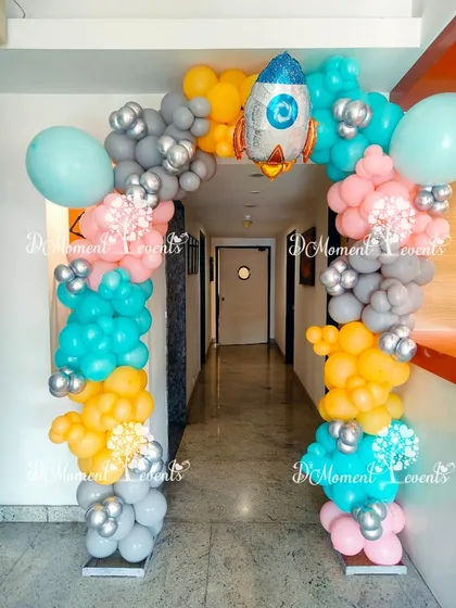 A space-themed balloon arch in bright colors with a rocket ship foil balloon, creating a fun entrance for an astronaut party.