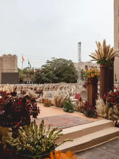 The wedding aisle at Fairmont Jaipur, lined with earthy florals and pampas grass, leading towards the grand fort-like entrance, creating a path of rustic elegance.
