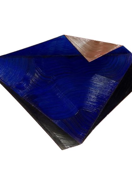 A textured sculpture where planes of deep cobalt blue, sleek black, and brushed copper meet in a geometric composition.