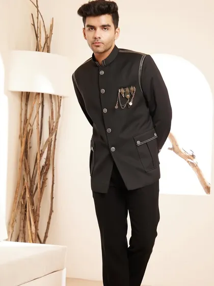 A modern interpretation of a timeless classic. This black bandhgala jacket features subtle leather piping and a distinctive metallic brooch, offering a sleek and sophisticated look for formal dinners and exclusive cocktail events.