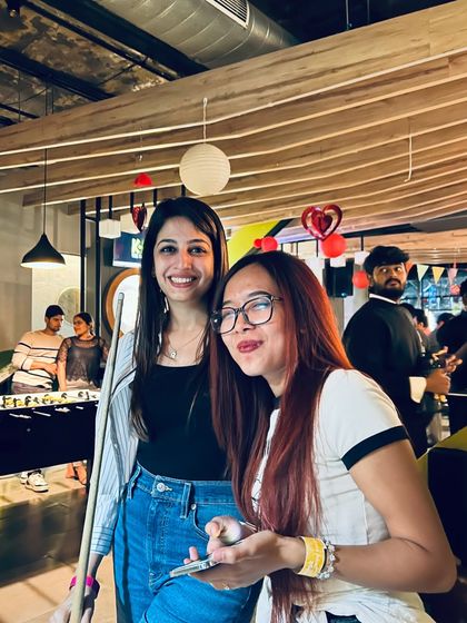 A couple enjoying a game of pool during a bustling Friday night. It's the perfect mix of games and party vibes.