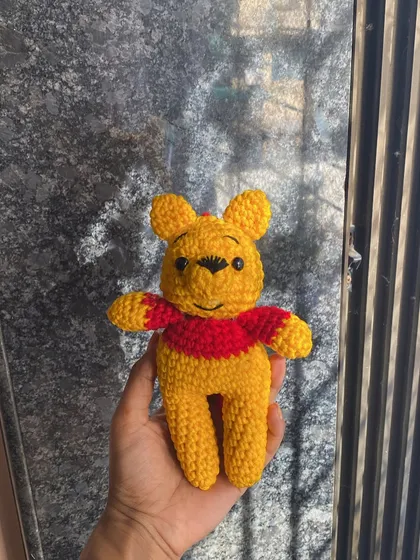 A clear, bright shot of the Winnie the Pooh amigurumi. You can see the detailed stitching on his face that gives him his gentle, friendly expression.