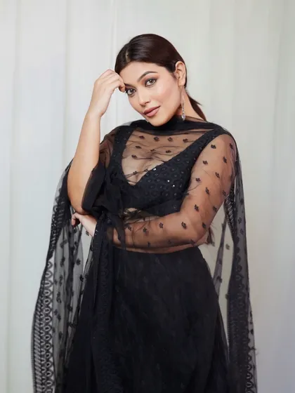 A classic portrait of the model in a black lehenga, looking at the camera with a gentle and confident expression.