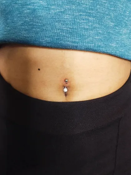 A navel piercing with a white pearl-style barbell. I can help you select from various jewelry materials and styles during your consultation.
