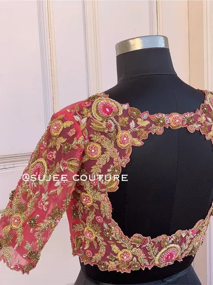 A sheer net blouse in a deep wine color with a large open back. The entire blouse is covered in intricate floral embroidery using zardozi and sequins.