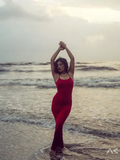 A collection of portraits featuring a model in a red dress on the rocks and by the water. The series explores different poses and moods, from serene to powerful.