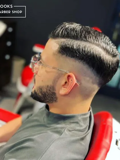 A side profile of a perfectly executed skin fade with a hard part. Notice the clean line-up and the smooth gradient, hallmarks of our detailed approach to men's haircuts.