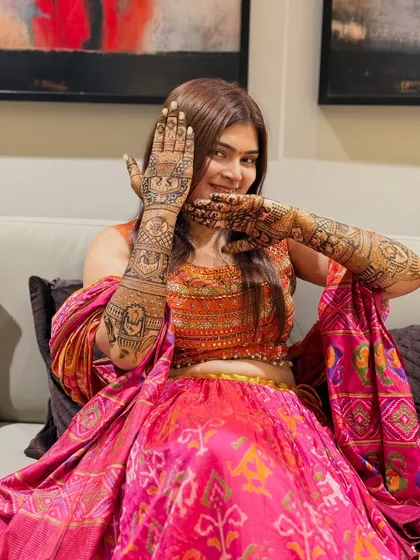 A happy bride posing with her stunning mehendi. The joy on her face is the best reward for the hours of artistry that go into creating her dream design.
