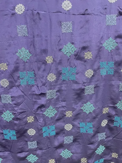 A close-up of the contemporary Kasuti embroidery on the navy blue silk. The different shades of blue thread add depth and movement to the geometric patterns.