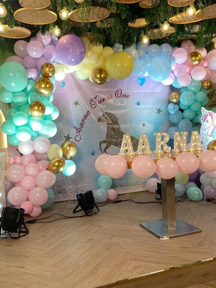 The full Unicorn party setup, including the backdrop, a cake table, and light-up letters spelling out the birthday girl's name.