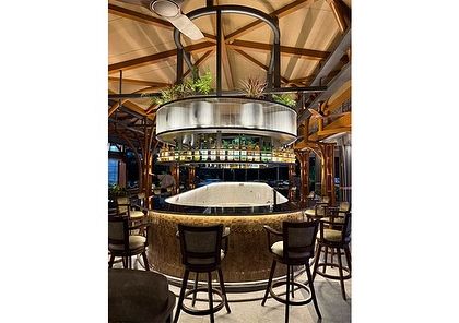 Another perspective of the circular bar at KGA. The hanging plants and overhead planters create a canopy effect, making the high-ceilinged space feel more intimate and connected.