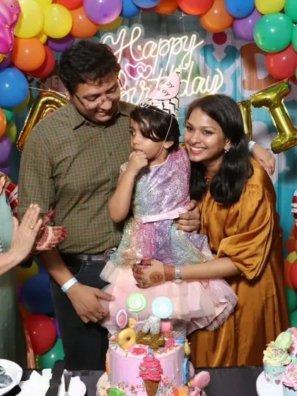 A sweet family moment during a Candyland-themed birthday party. The colorful backdrop and amazing cake make the photo even more special.