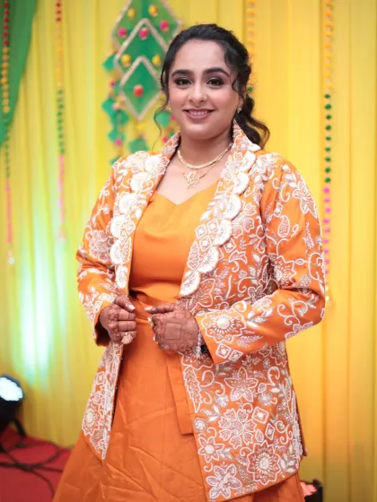 A full-length view of the bride's orange Mayera outfit. The styling is elegant and comfortable, perfect for a long day of rituals.